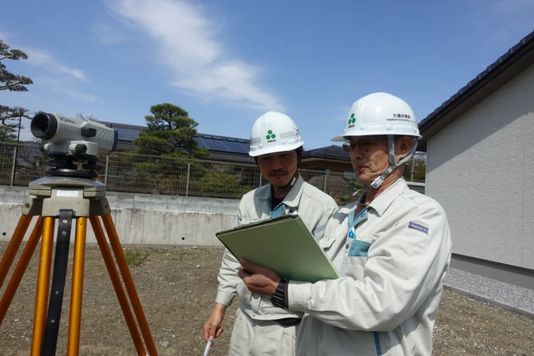 建築前の敷地で測量機器を使用し土地調査を行う矢橋林業のスタッフ