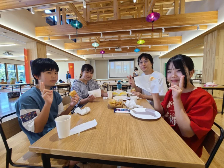 木のぬくもりあふれる会場で軽食を楽しむ来場者家族の団らん風景