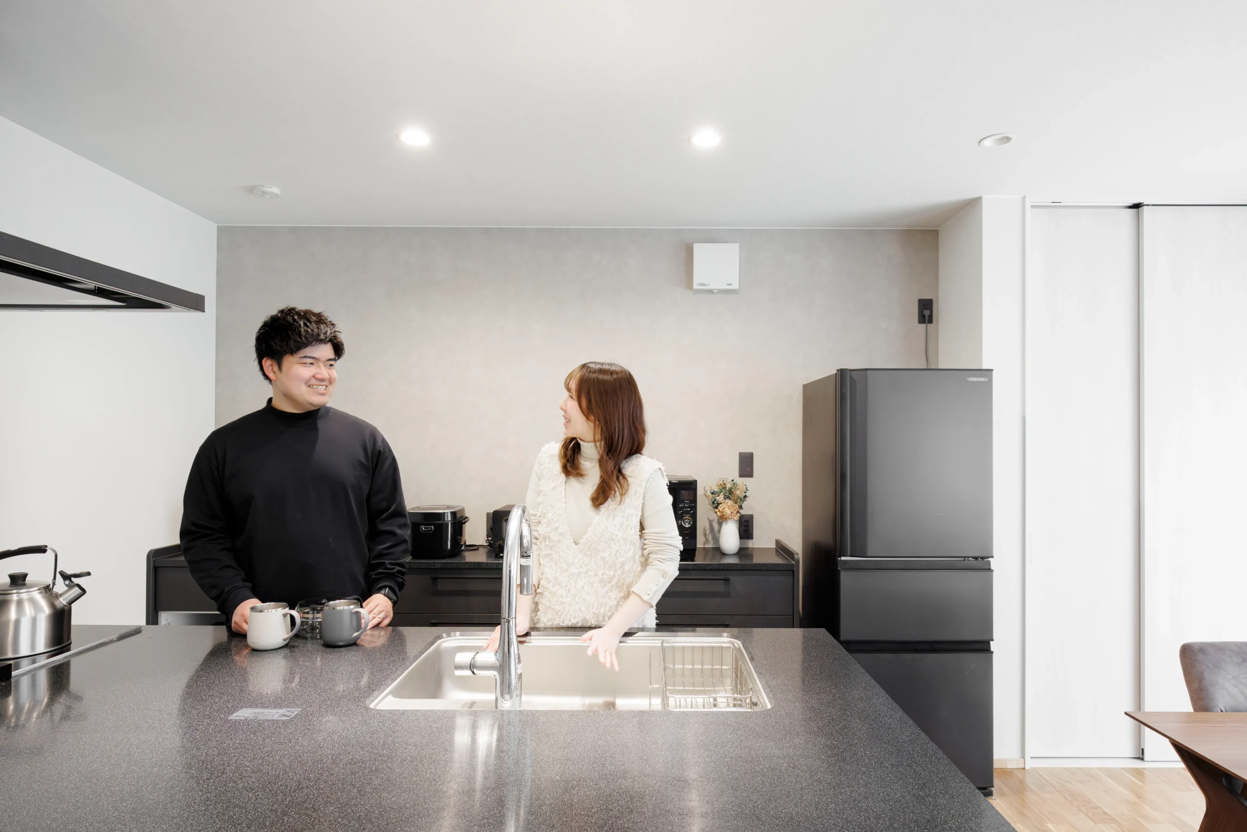 アイランドキッチンを囲みながら会話を楽しむ夫婦の暮らし風景
