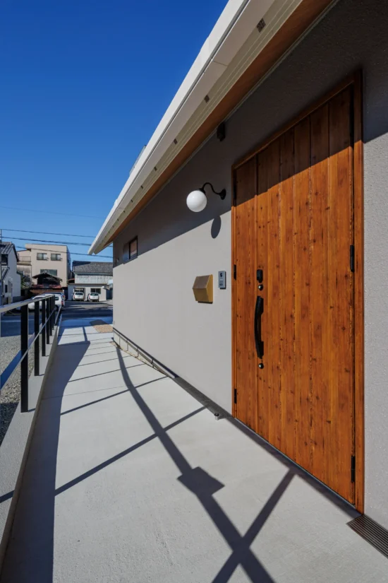 バリアフリー設計のスロープと木製玄関ドアを備えた平屋住宅